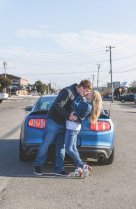 couple kissing by blue mustang