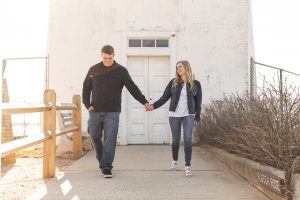 couple holding hands walking by light house