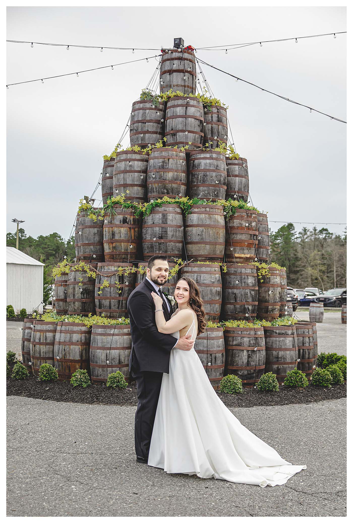 wedding couple standing in front of tree made of wine barrels