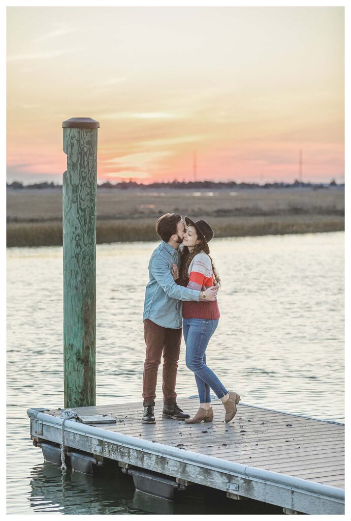 couple standing on dock with sunset