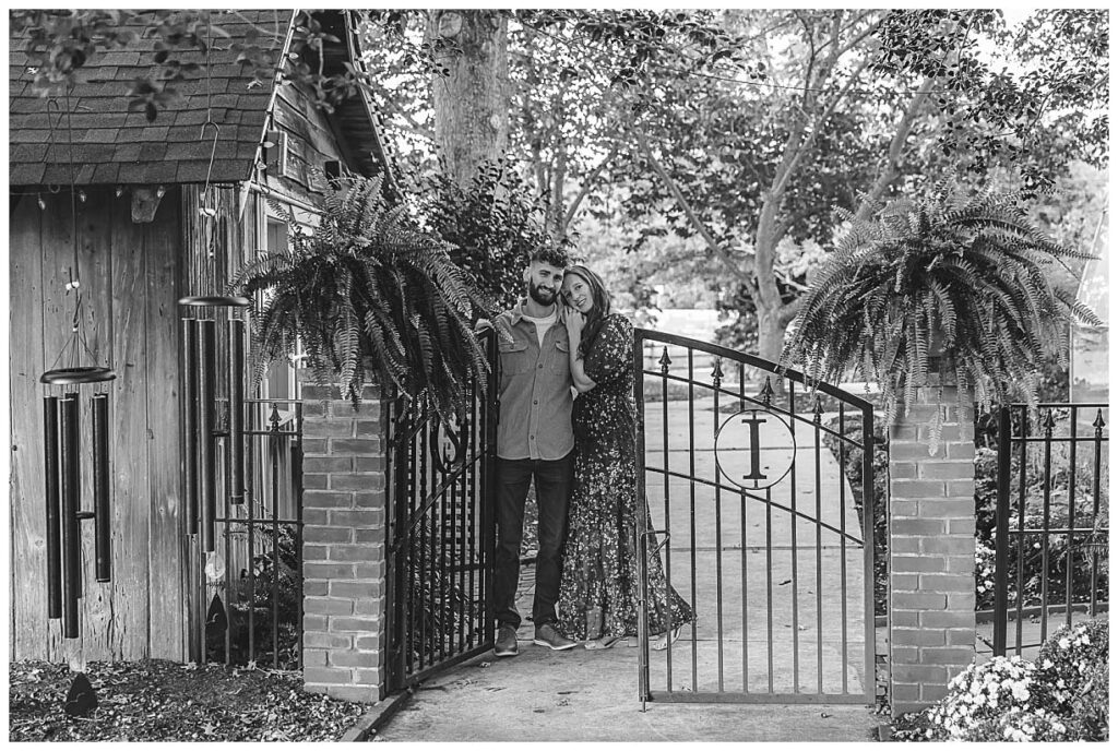 engaged couple standing by black gate at smithville inn