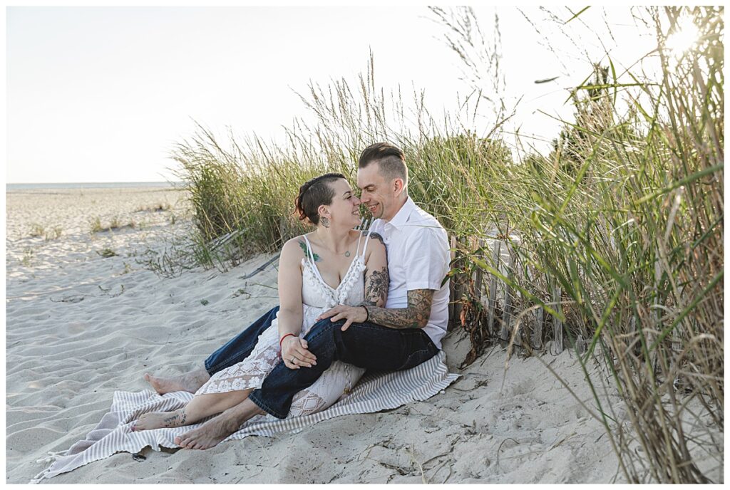 an engaged couple sitting on beach in Cape May NJ