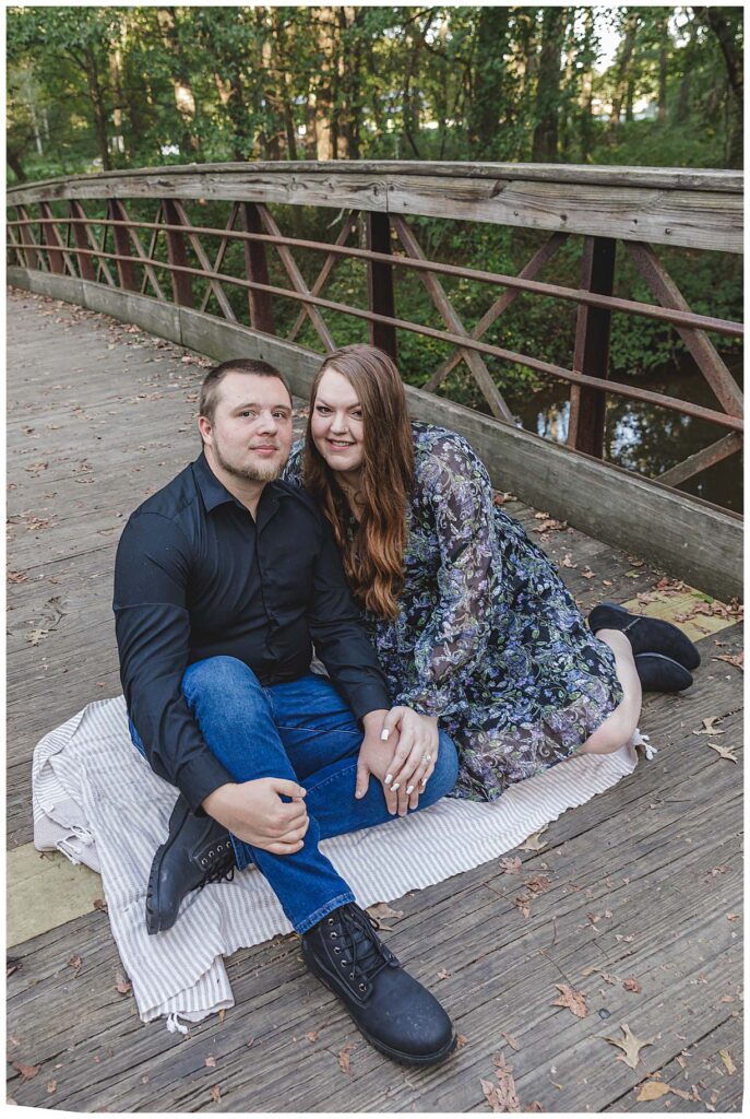 sitting on a bridge for their engagement session