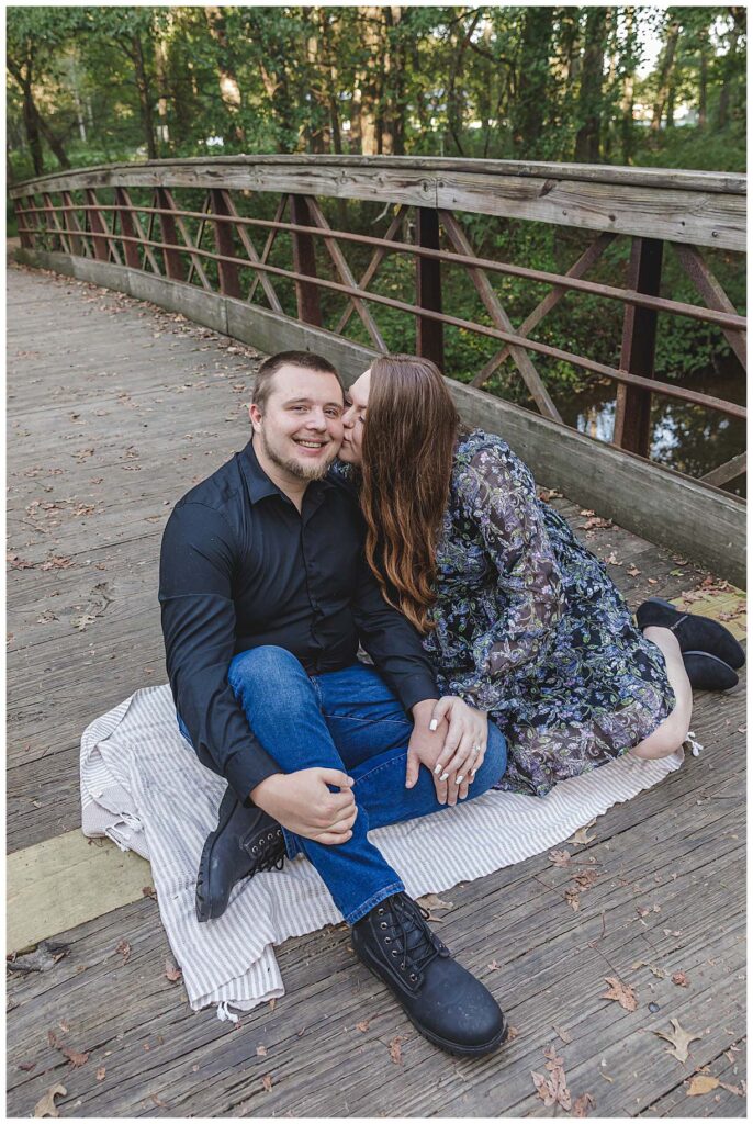sitting on a bridge for their engagement session in mercer county