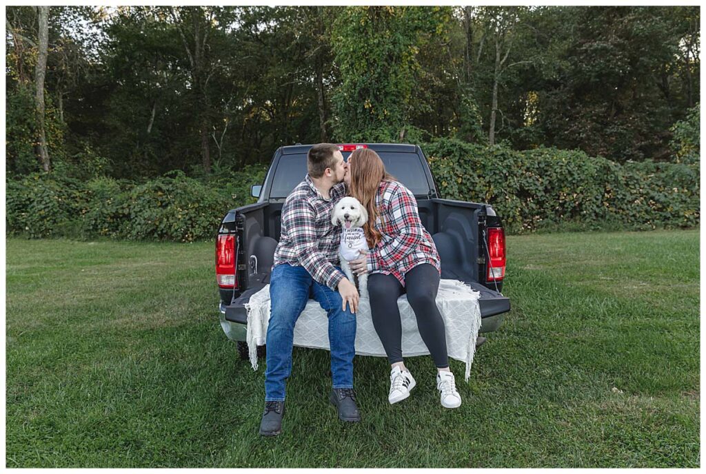 couple sitting with their dog in the back of the pickup truck
