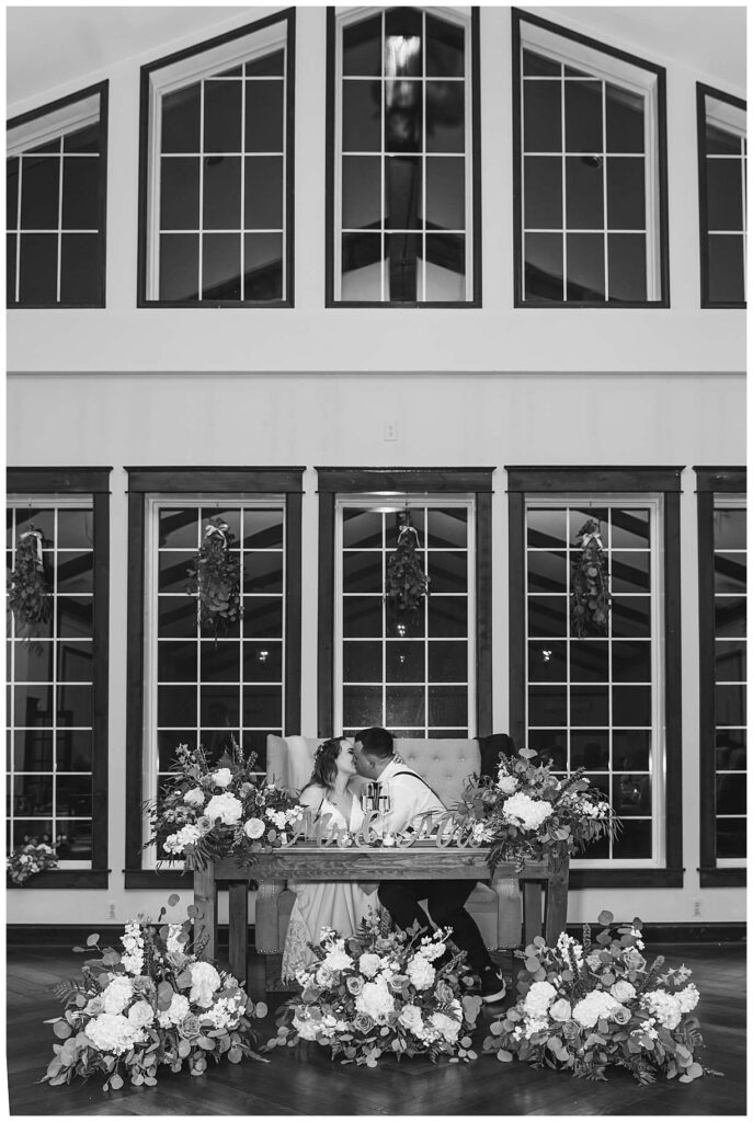 black and white of wedding couple sitting in front of the big tall windows
