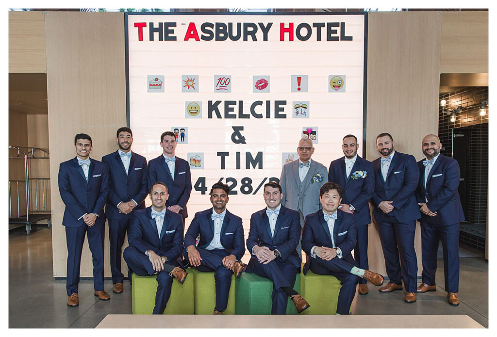 groom and groomsmen standing in front of sign