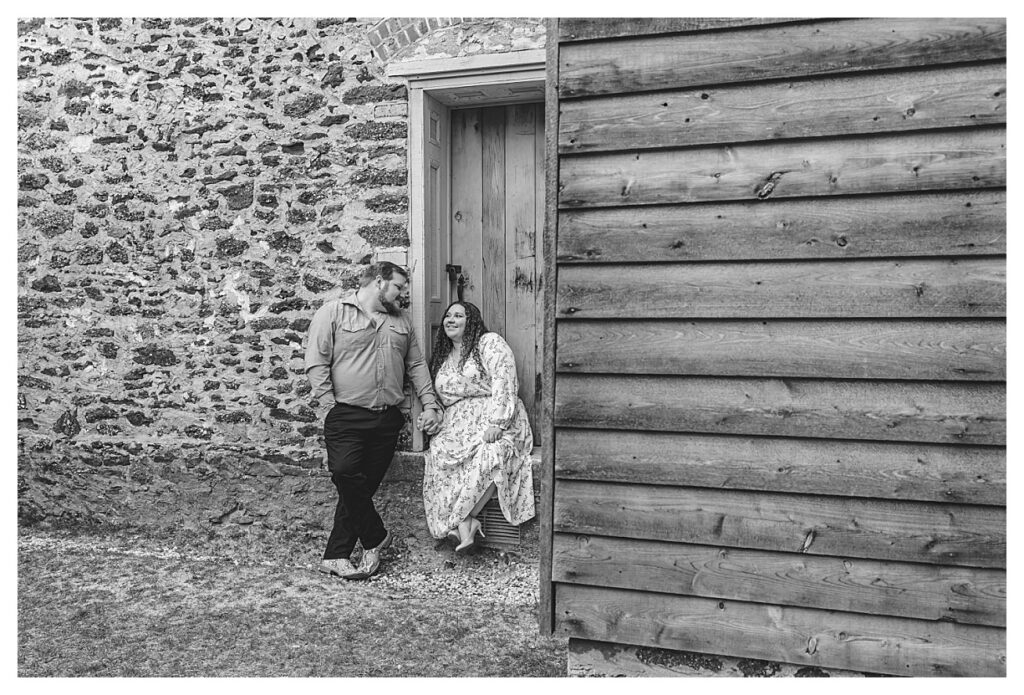 black and white of couple sitting by blue door