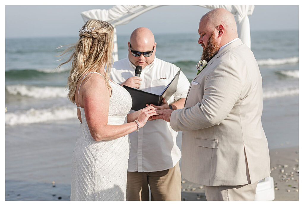 couple putting on the rings at a beach wedding in ocean city