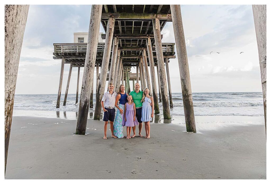 family standing under the pier in Ocean city new jersey for their south Jersey beach photography