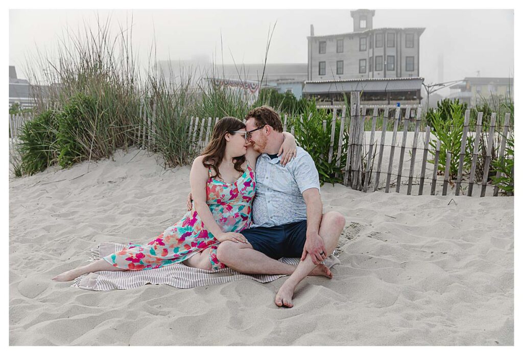 couple sitting on the beach in the fog in cape may for an engagement session