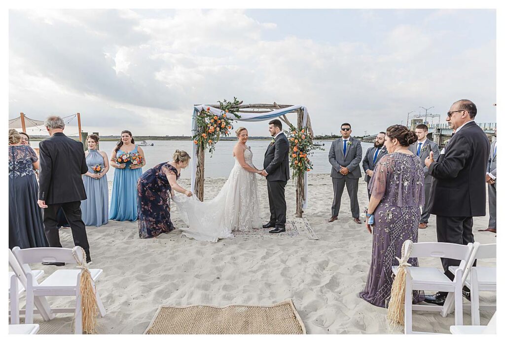 maid of honor fixes the brides dress for their beach wedding at the Deauville inn