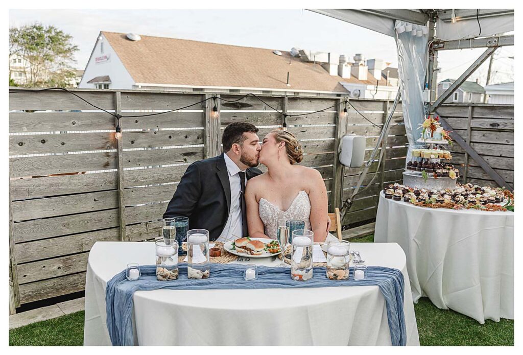 couple kissing at the sweetheart table at the fall coastal wedding